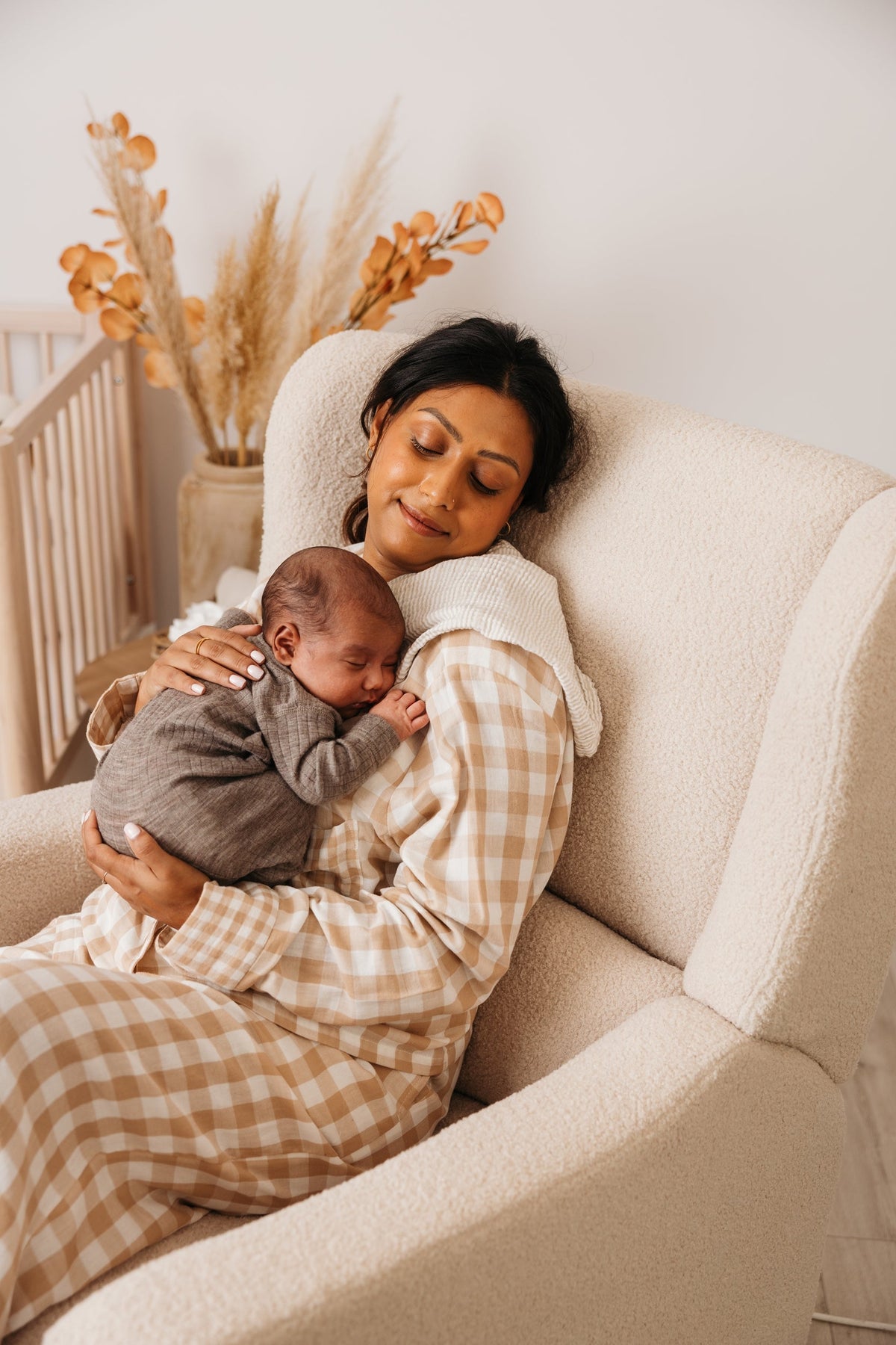 Close up of a sleeping newborn on a mother in the Lyra nursing chair in Biscuit Bouclé