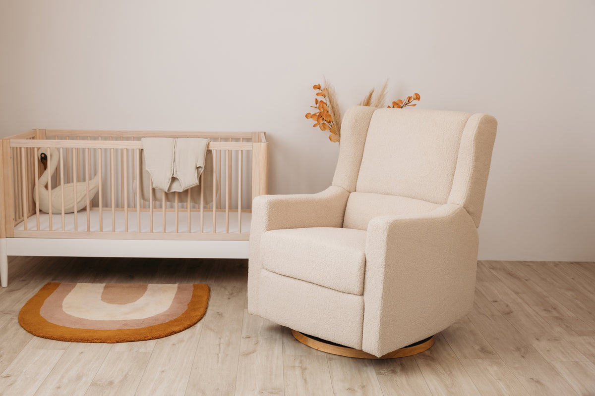Gaia Baby Lyra Electric Recliner Nursing Chair in Biscuit Bouclé beside a cot in a neutral nursery