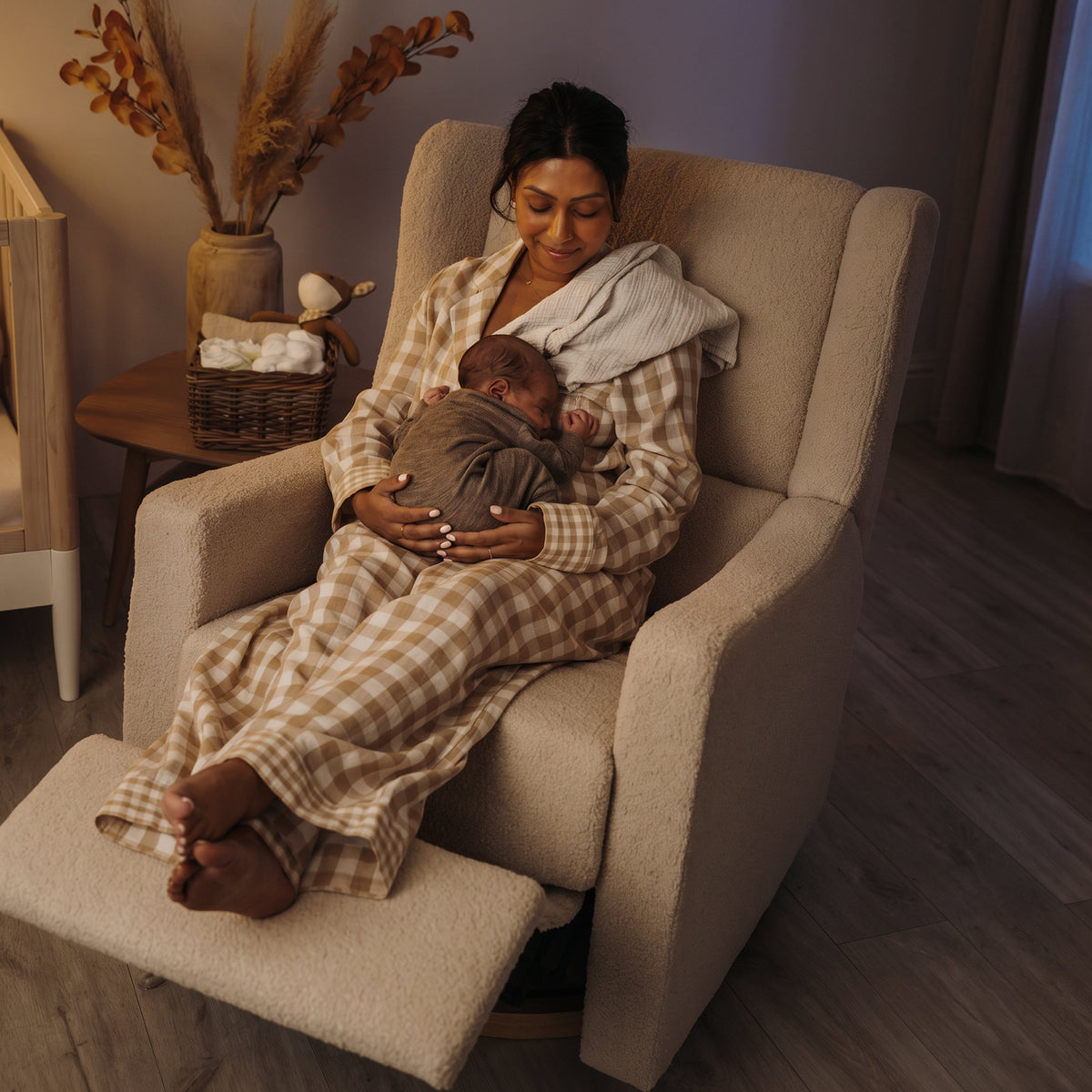 Mother feeding her newborn in the Lyra electric recliner in Biscuit Bouclé at night