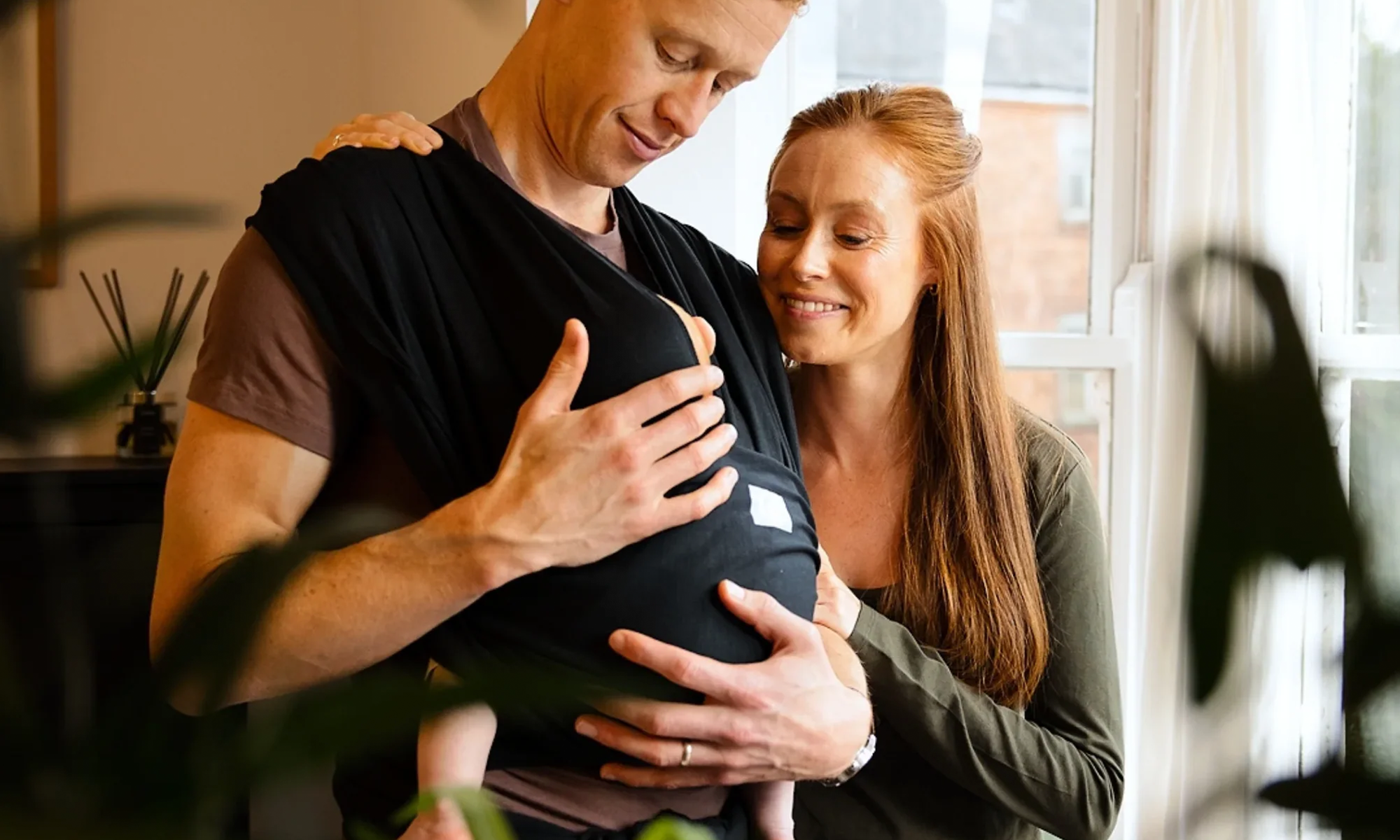 Parent wearing newborn baby in Gaia Baby Stretchy Baby Wrap
