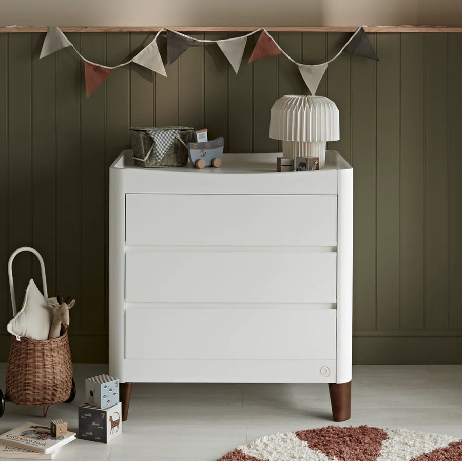 White Gaia Baby Serena dresser with walnut legs, featuring sleek design and spacious drawers for nursery storage.