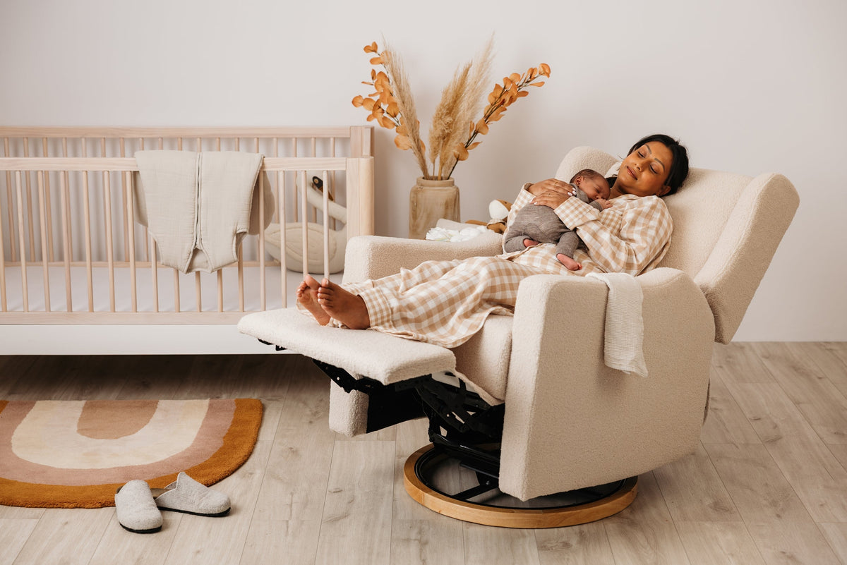 A mother resting with her baby in Lyra, reclined beside the cot