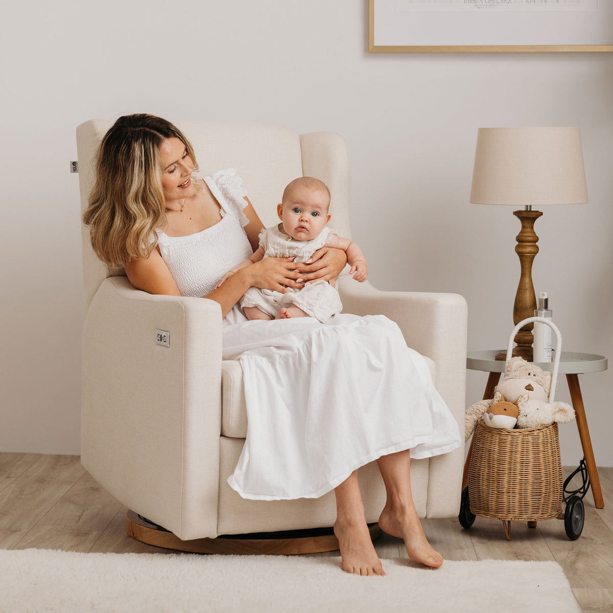 Mother holding her baby in the Gaia Baby Lyra nursing chair in Oat