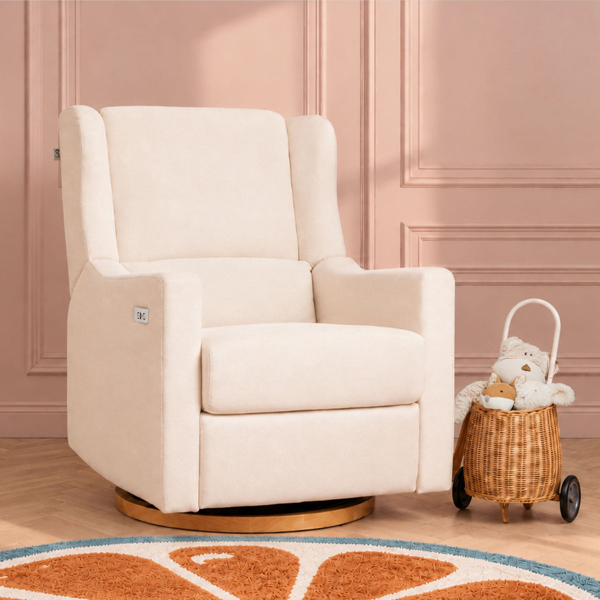 Gaia Baby Lyra Electric Recliner Nursing Chair in Oat in a blush nursery with a wicker toy pram
