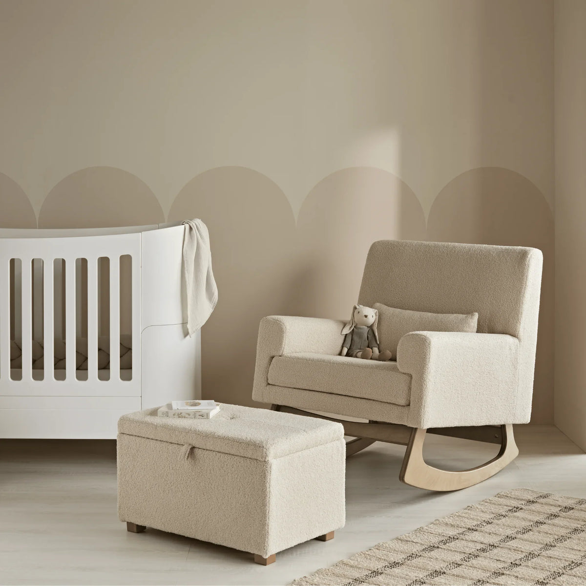 Gaia Baby Serena rocking chair in Biscuit Bouclé with the matching storage footstool beside a white cot