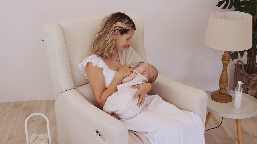 Mother feeding her baby in the Gaia Baby Lyra nursing chair in Oat